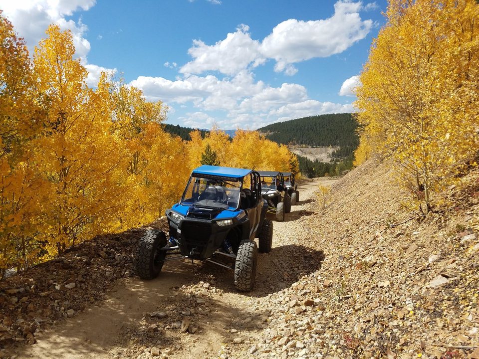 A Polaris RZR on a mining road in the aspens